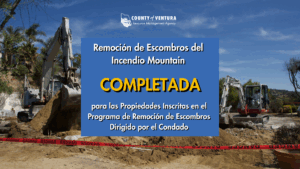 Excavadoras en un sitio de remoción de escombros con un letrero que dice "Remoción de Escombros de Incendio de Montaña Completada".