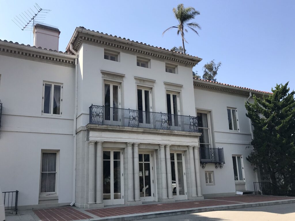 Front entrance of Thomas R. Bard Mansion with white columns and decorative balcony.