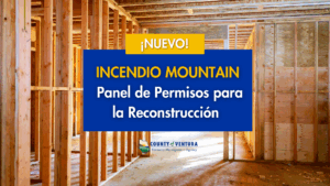 Vista interior del armazón de madera de un edificio en construcción con texto: "¡Nuevo! Incendio Mountain Panel de Permisos para la Reconstrucción."